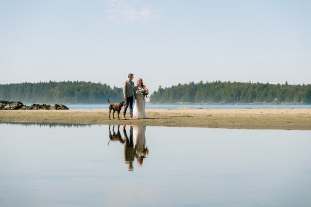 Couple reflected in still water at beach sunset